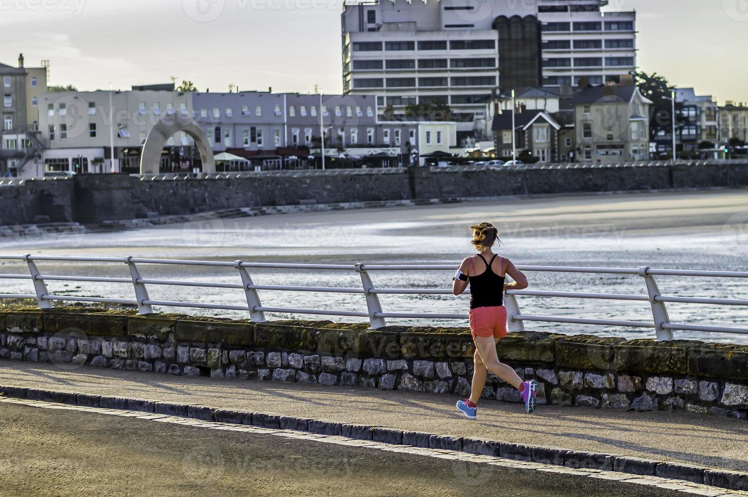 woman, jogging, morning run on the sea front, colour image. photo
