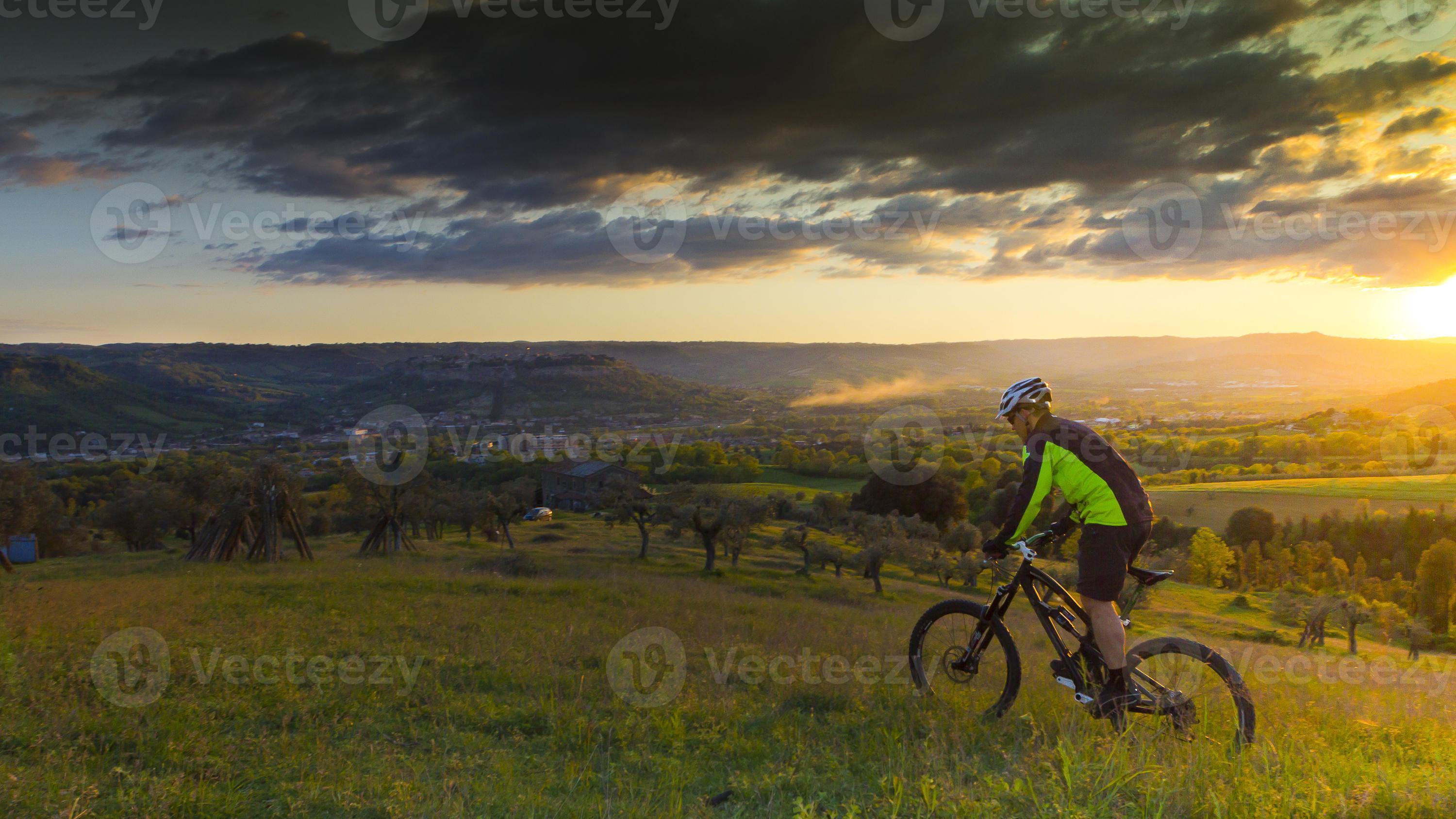 hombre en bicicleta de montaña, puesta de sol foto
