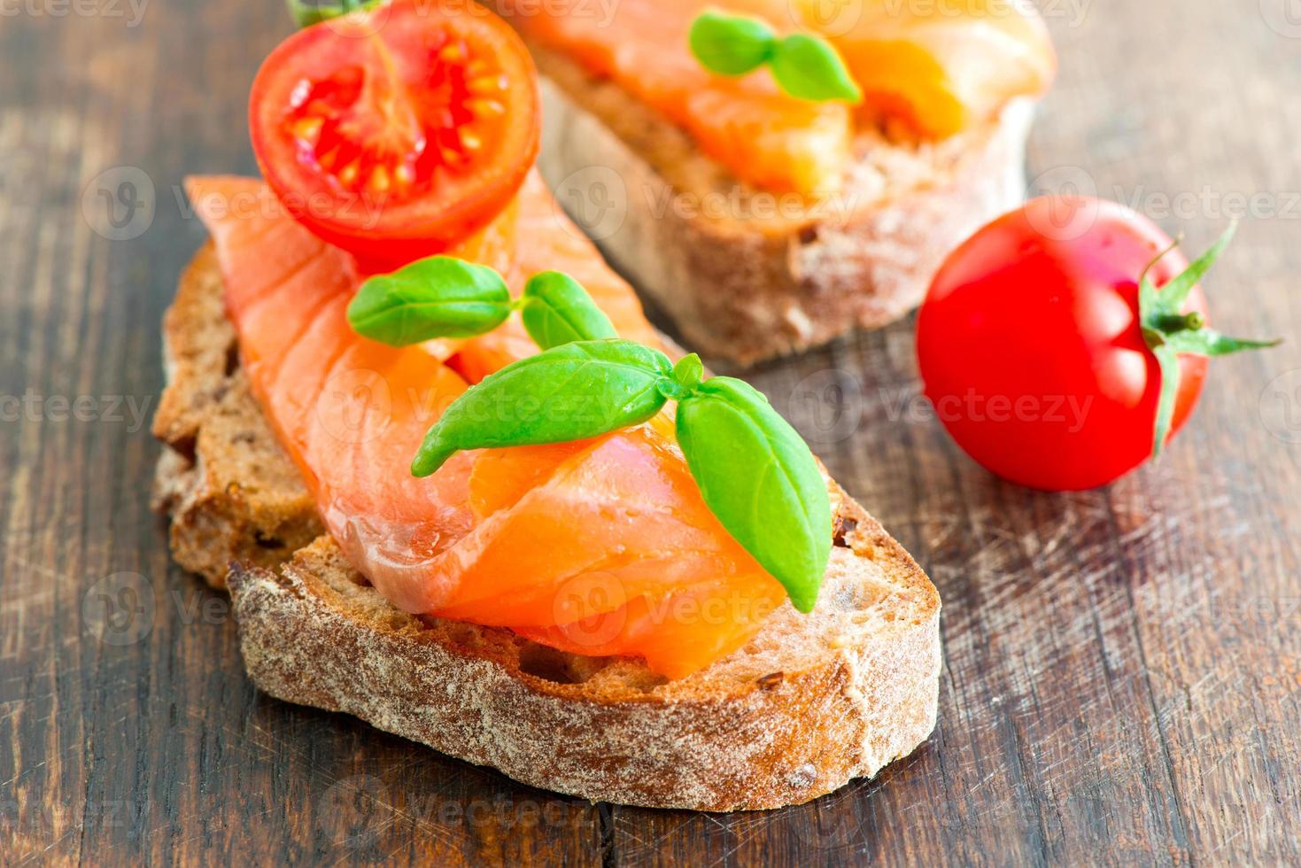 Sandwich de salmón en mesa de madera con tomate foto