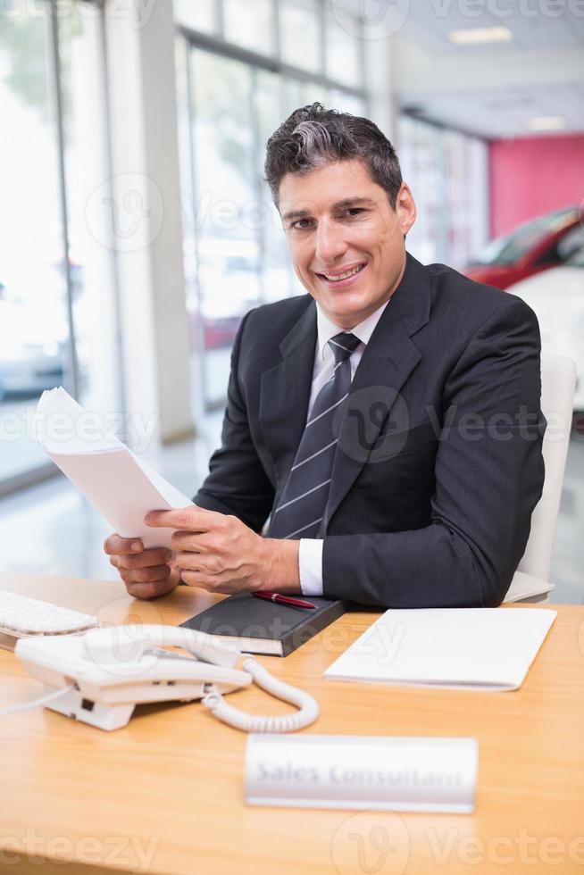 vendedor sonriente sosteniendo un documento foto