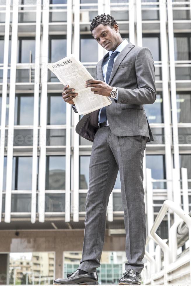 hombre de negocios negro leyendo el periódico al aire libre foto
