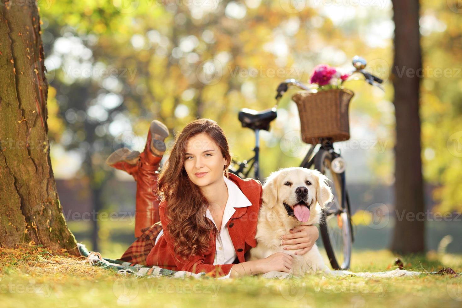 Pretty young female lying down with dog in a park photo