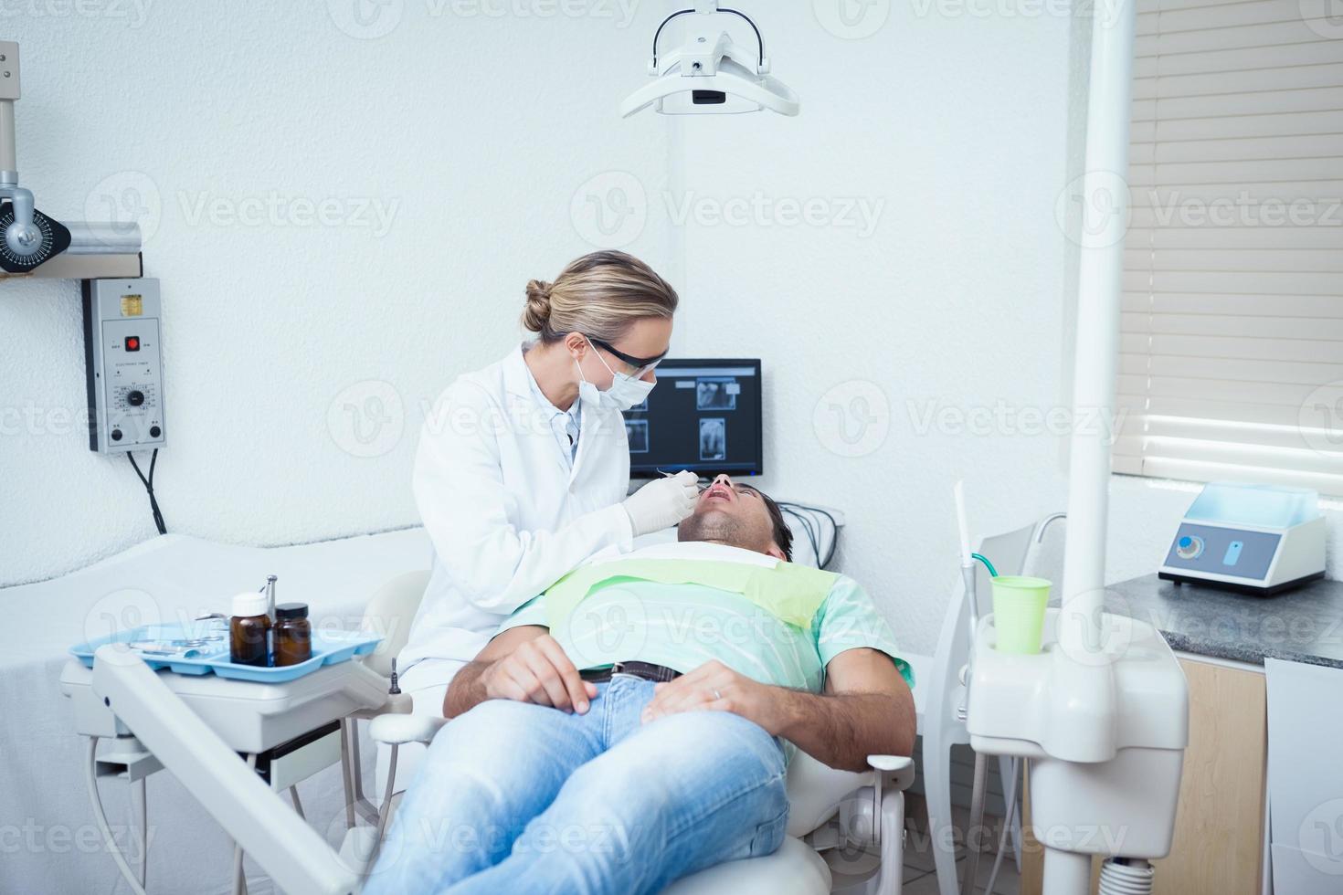 Female dentist examining mans teeth photo