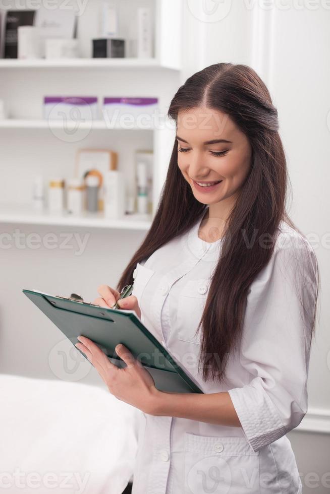 Beautiful female cosmetician is making an appointment photo