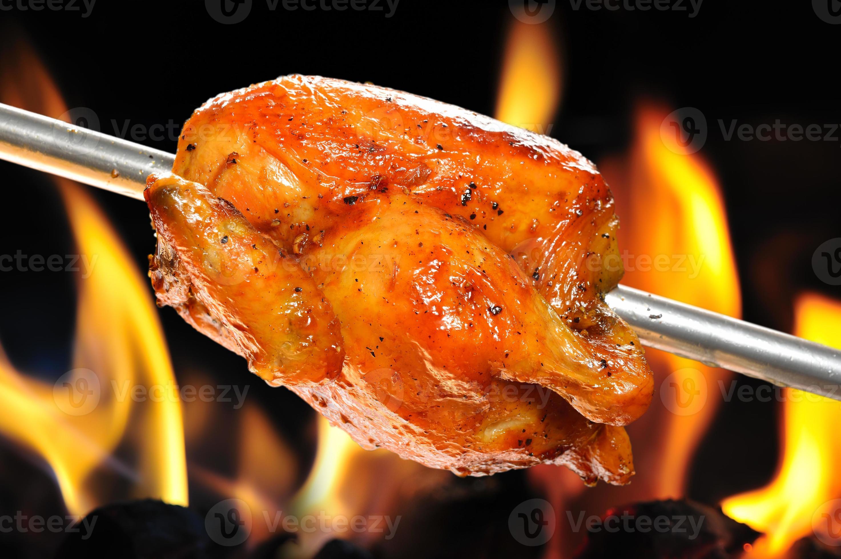 Glazed rotisserie chicken being roasted over an open fire 758254 Stock