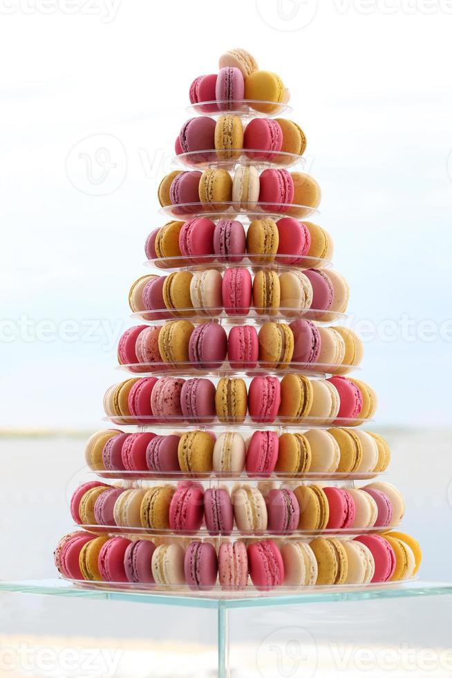 Muchos macarons franceses tradicionales coloridos en un pastel están parados en foto