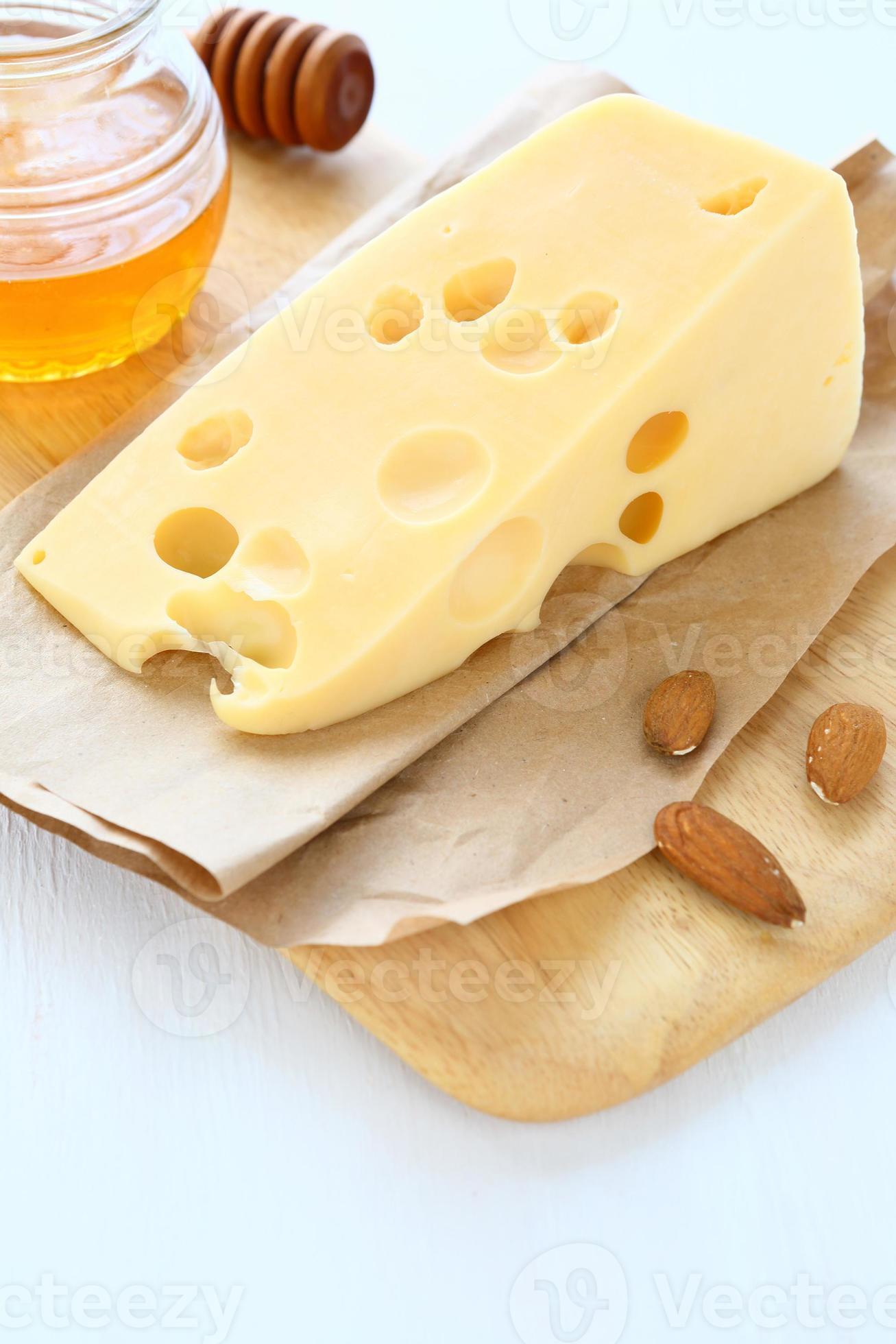 trozo de queso en una tabla con almendras y miel foto