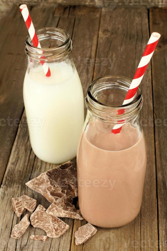 Chocolate and regular milk in bottles on wood photo