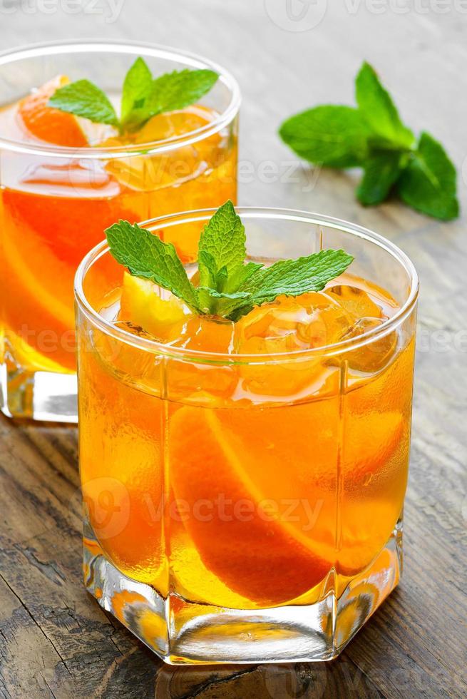 Cold drinks with ice and mint. Orange cocktail on rustic photo