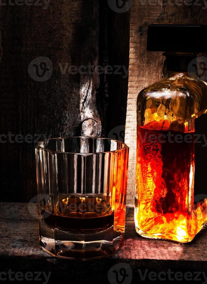 Vaso de whisky escocés y botella sobre fondo de madera vieja. foto
