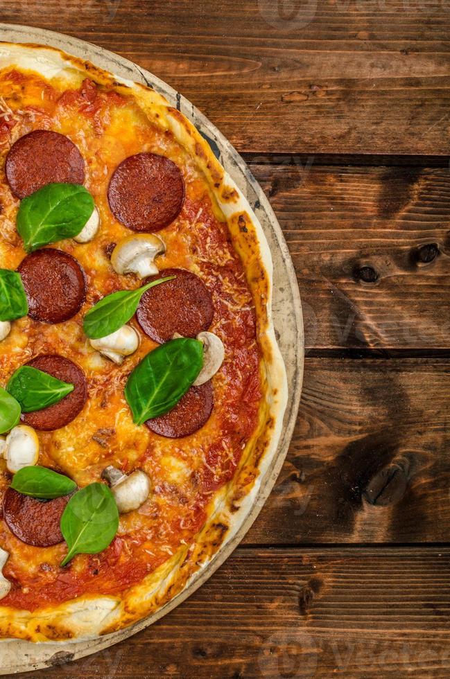 Rustic pizza with salami, mozzarella and spinach photo