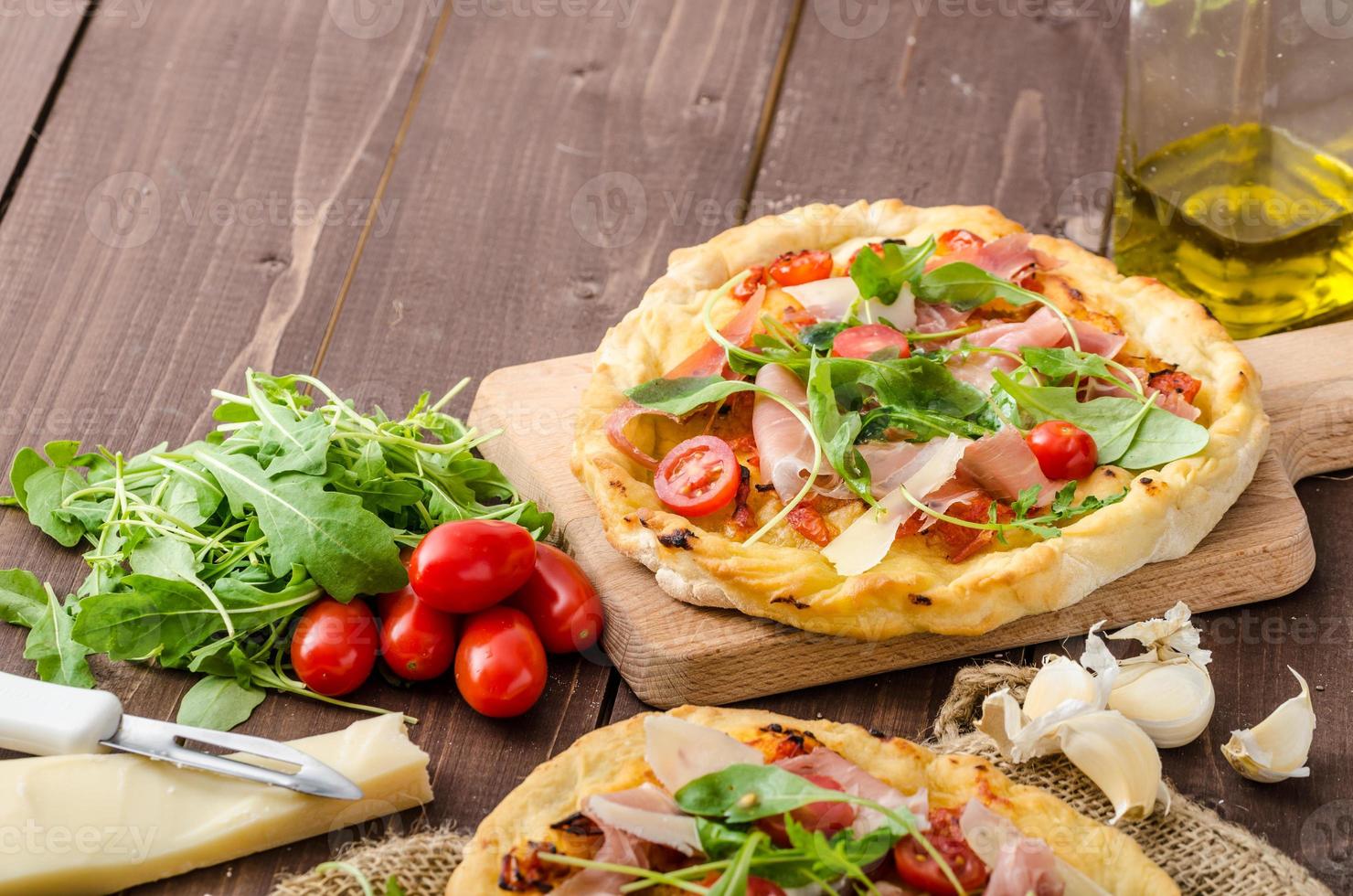 pizza italiana con queso parmesano, prosciutto y rúcula foto