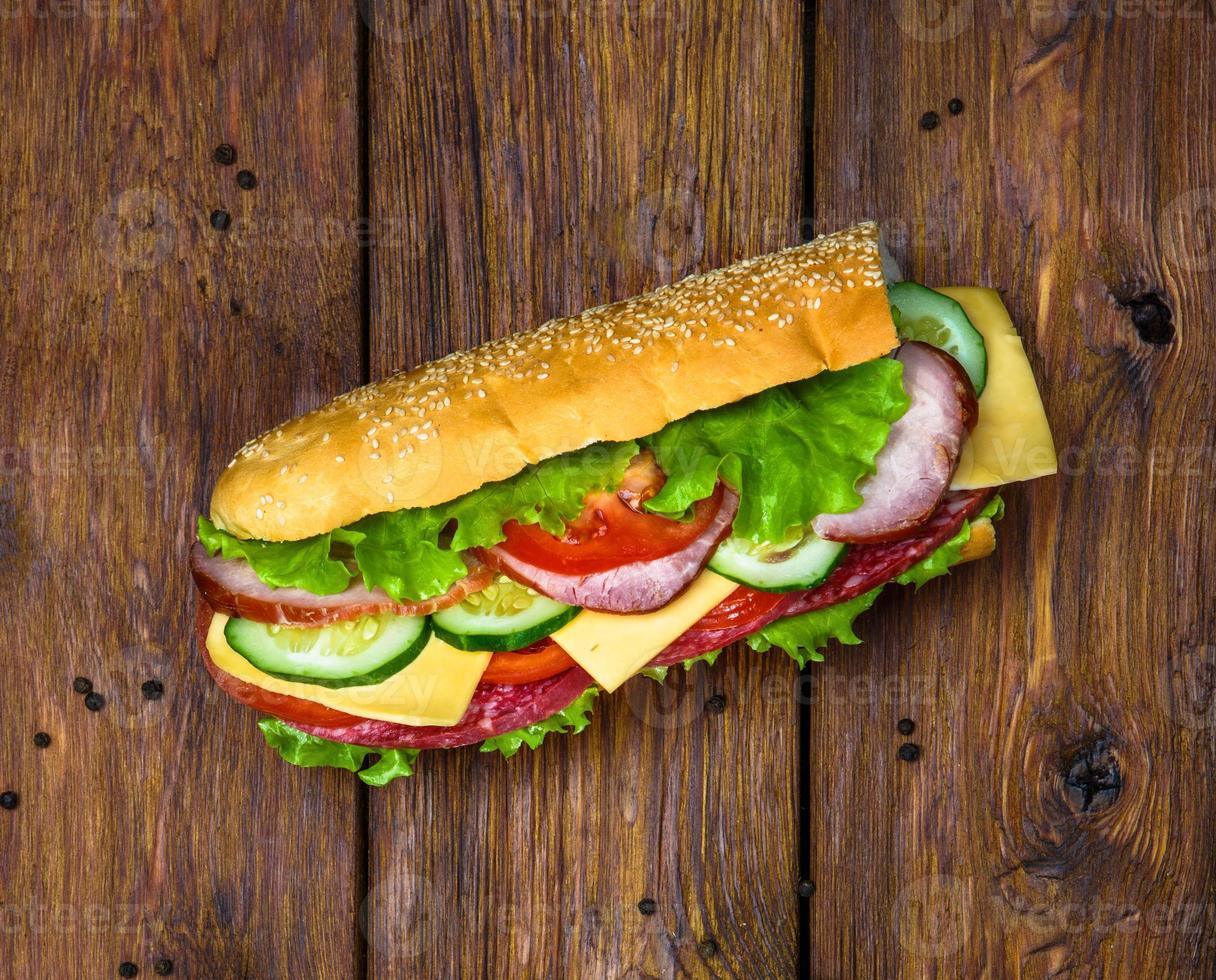 Sandwich with meat and vegetables on wood photo