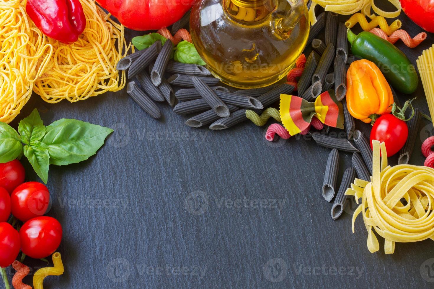 Raw pasta with ingridients on black board photo
