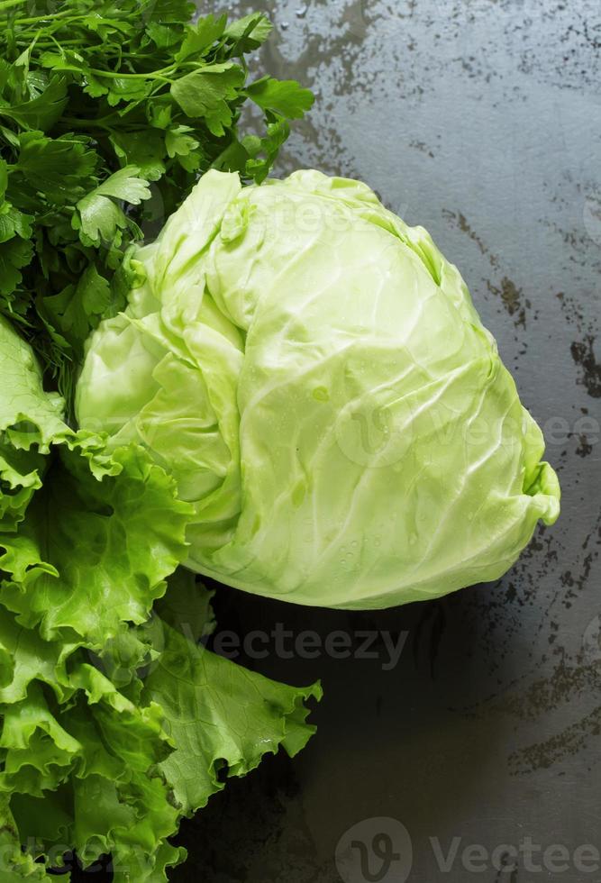 Fresh cabbage, lettuce, parsley on a wooden table, selective foc photo