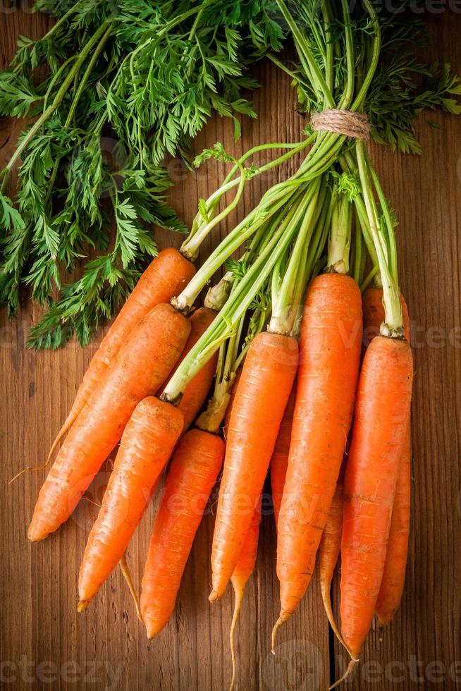 fresh organic carrots bunch on wooden background photo