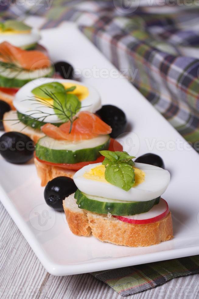 canape with boiled egg, cucumber, radish, salmon vertical photo