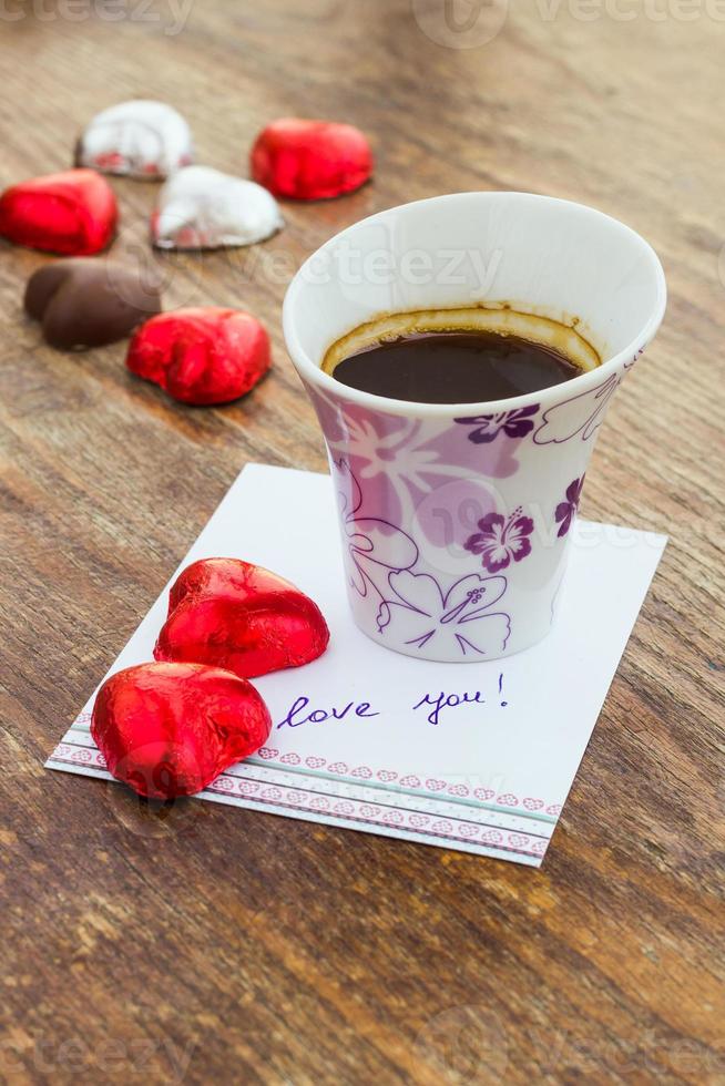 Card with love message, cup of coffee and chocolate candy photo