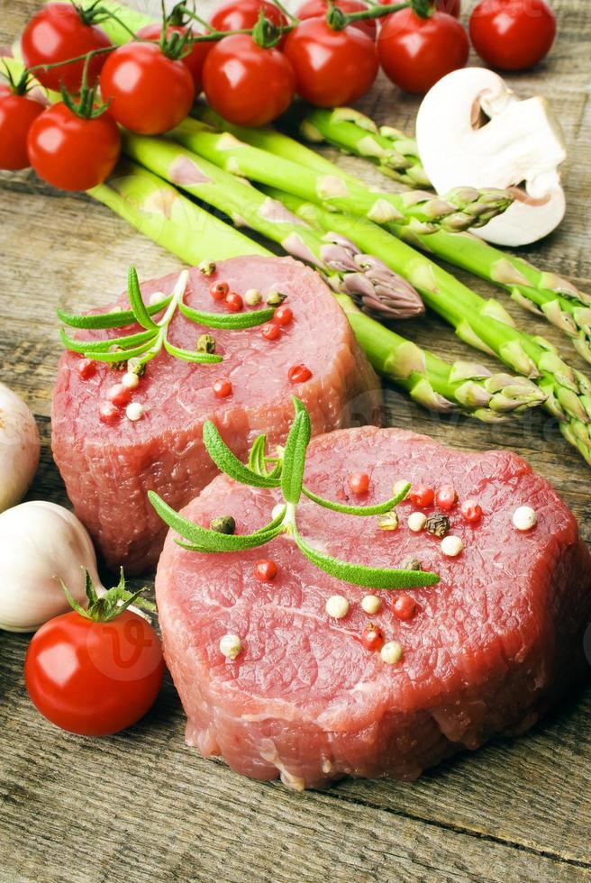 Raw Steak with green asparagus on wooden board photo