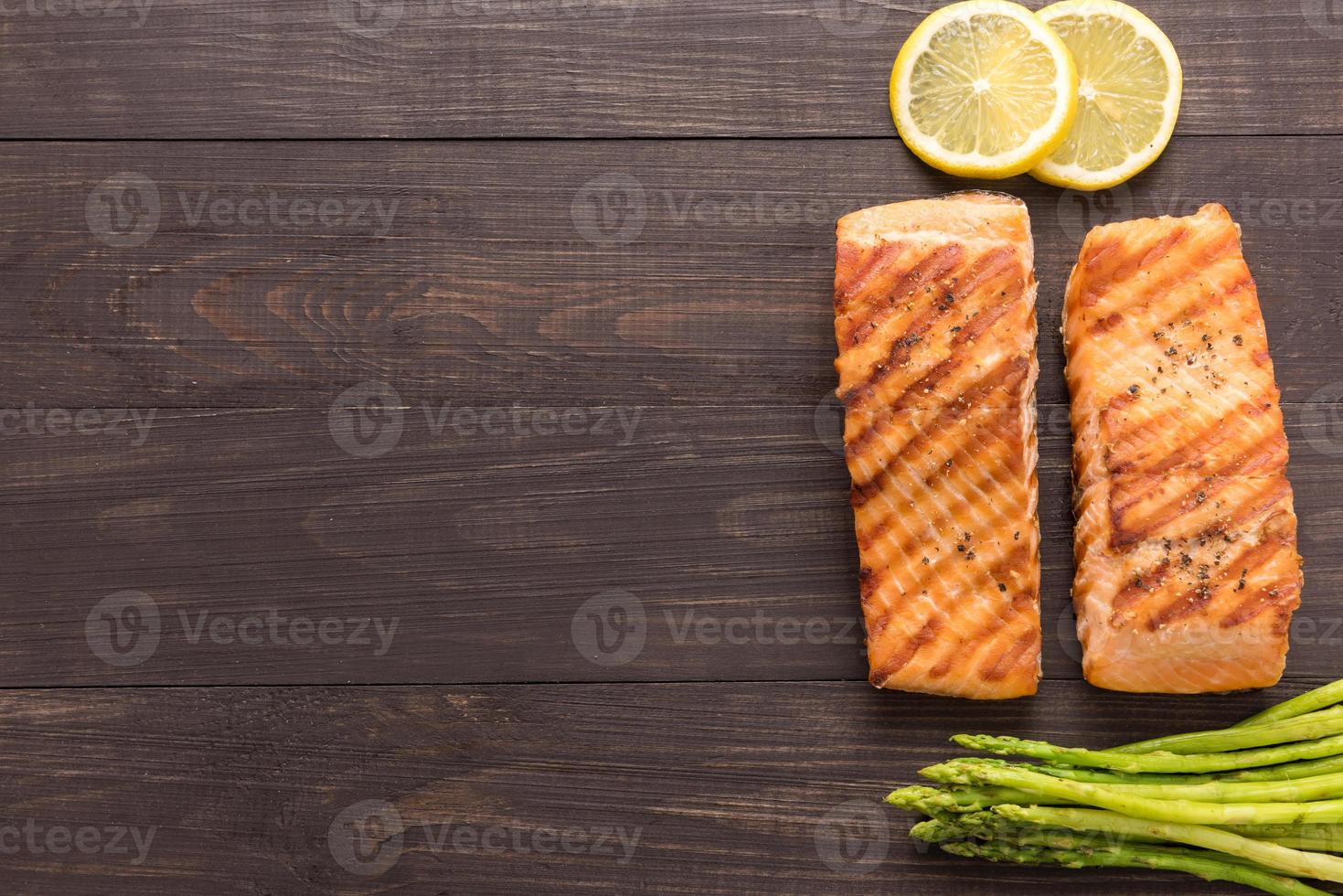 Grilled salmon with lemon, asparagus on wooden background photo