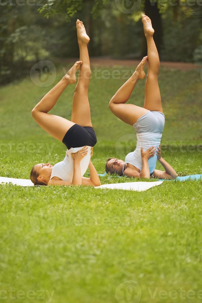 Clase de condicionamiento fisico. hermosas mujeres jóvenes haciendo ejercicio en el parque de verano foto