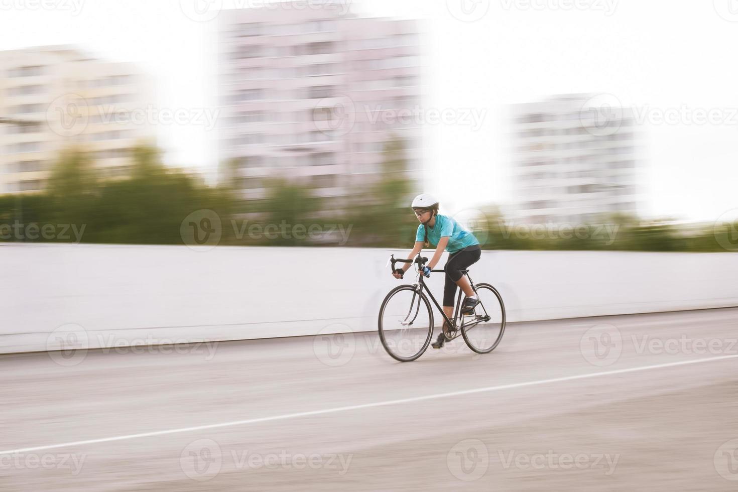 young female athlete racing on a bike. motion blurred image photo