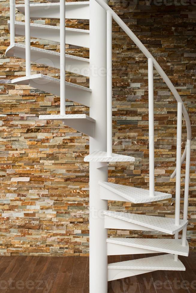 White spiral staircase on stone wall photo