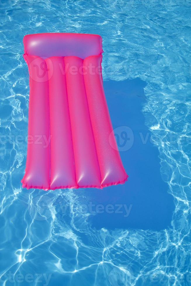 cama de aire rosa flotando en una piscina foto