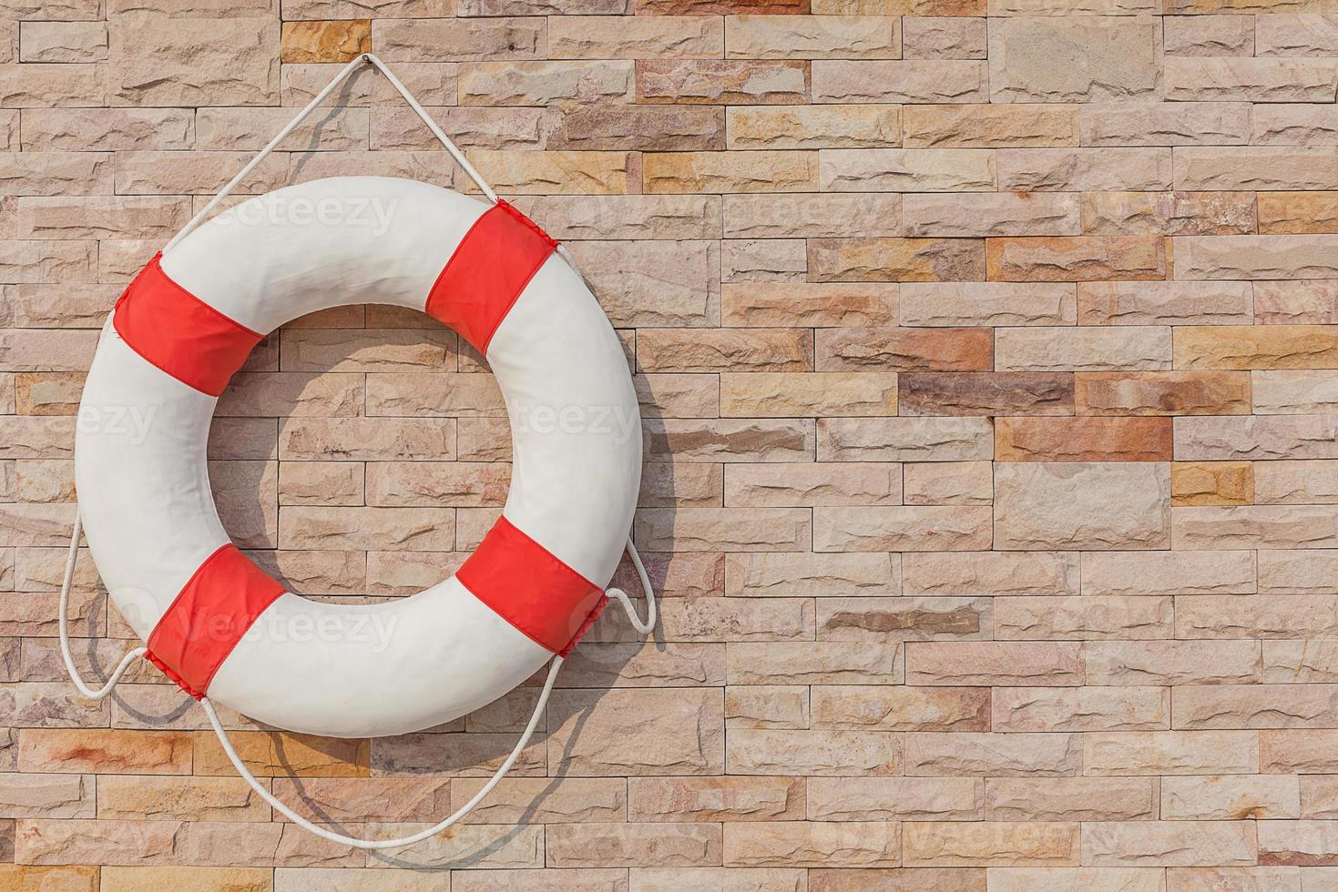 The life buoy is hanged on brick wall background. photo