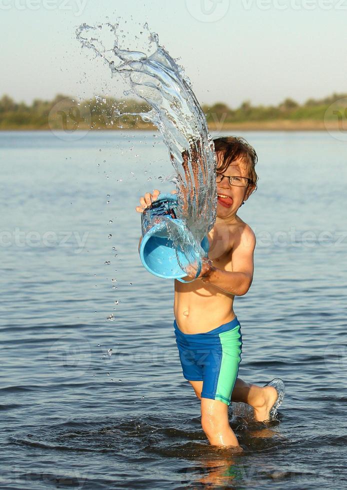 little boy throwing water from bucket at river 788117 Stock Photo at