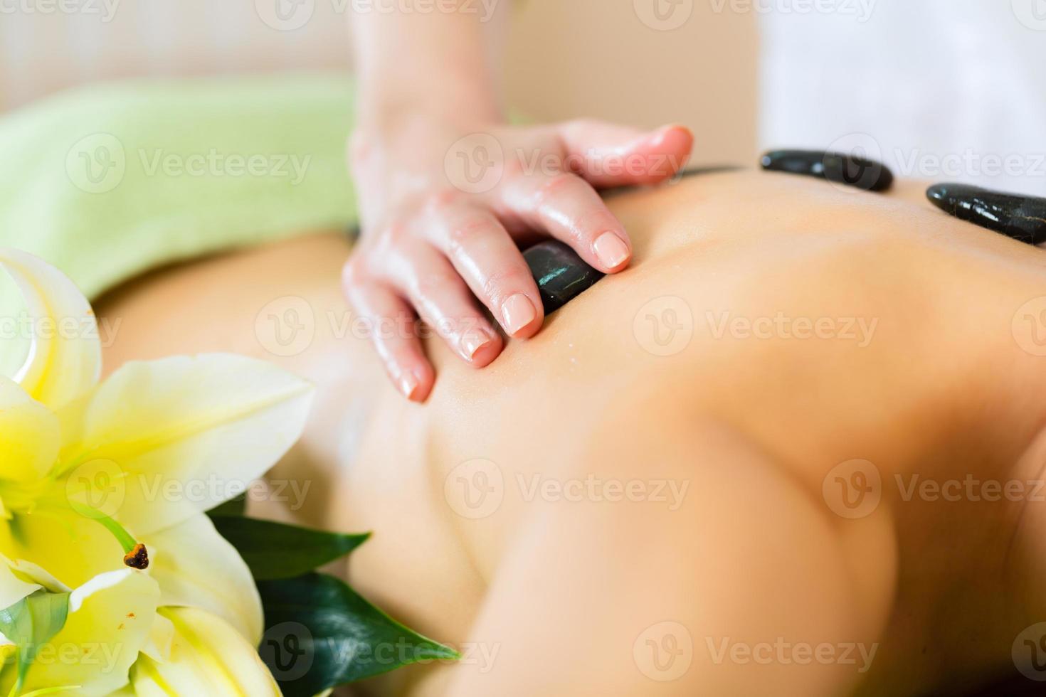 mujer teniendo bienestar masaje con piedras calientes foto