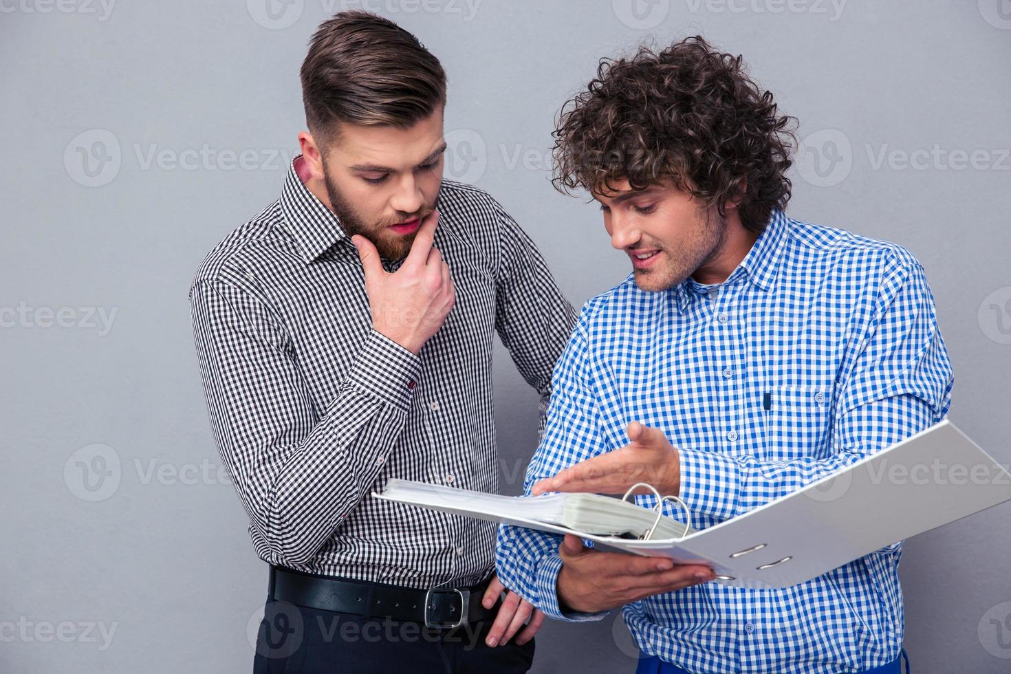 Two casual businessmen reading documents in folder photo