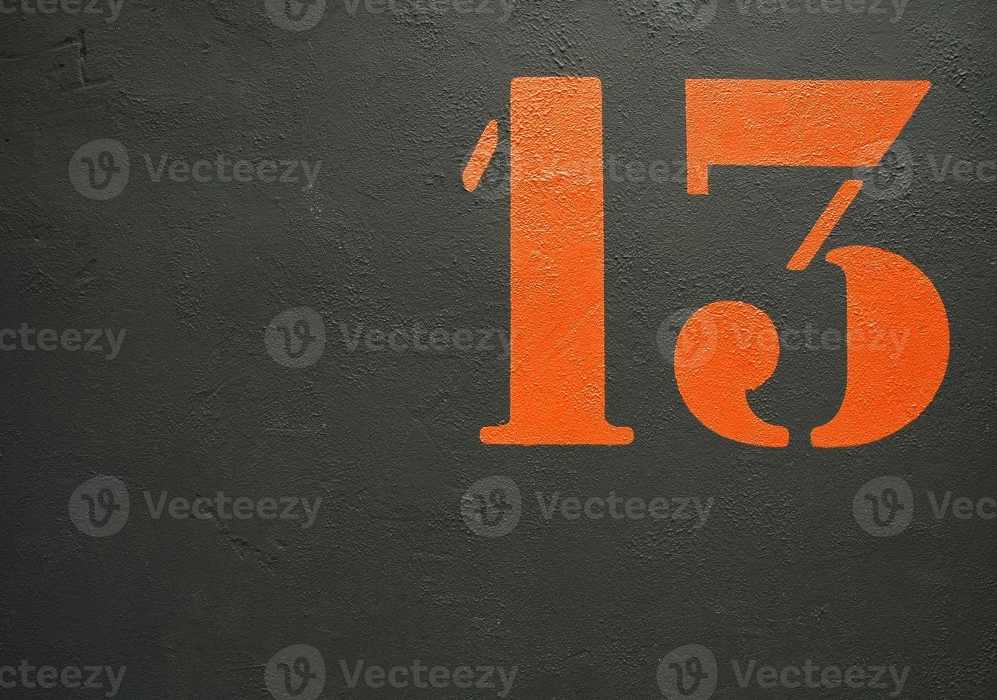 An orange stenciled number 13 on a black background photo