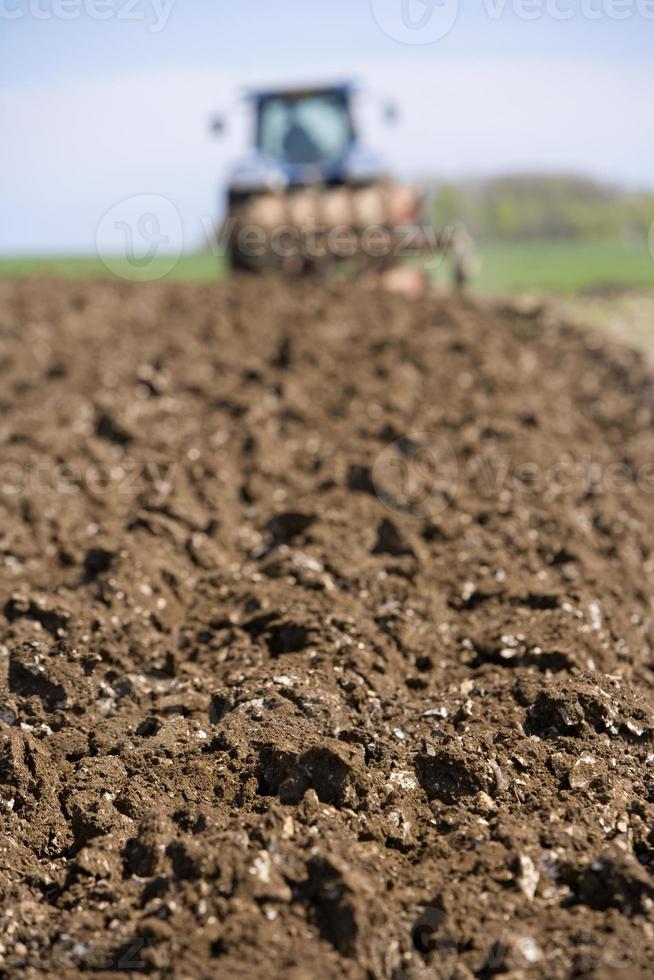 Close up of ploughed field with tractor and plough photo