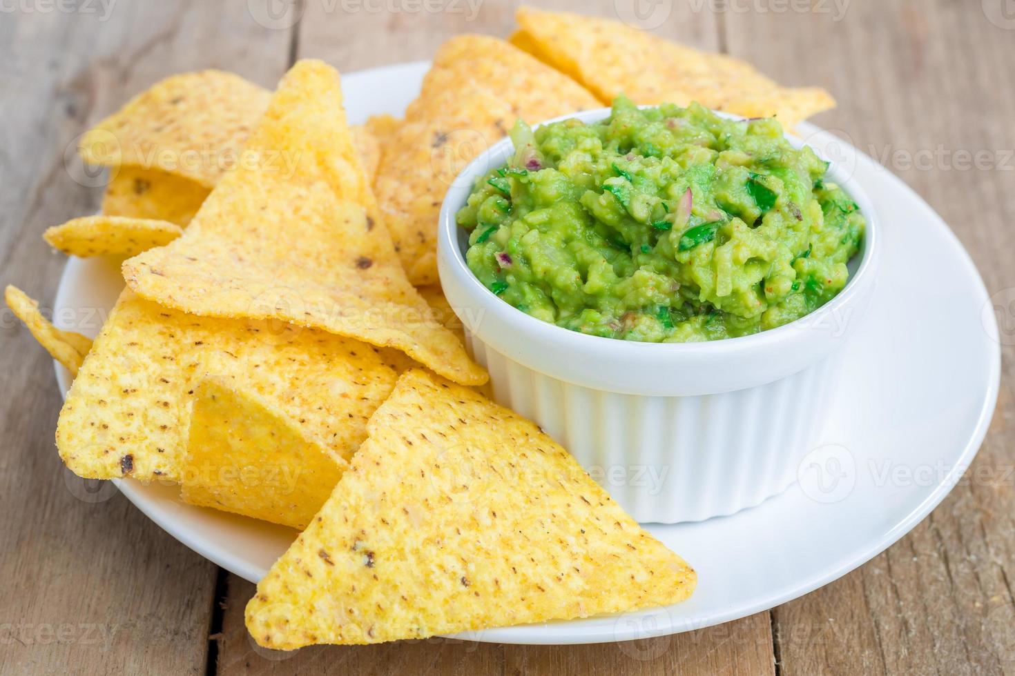 Cup with chunky guacamole served with nachos photo