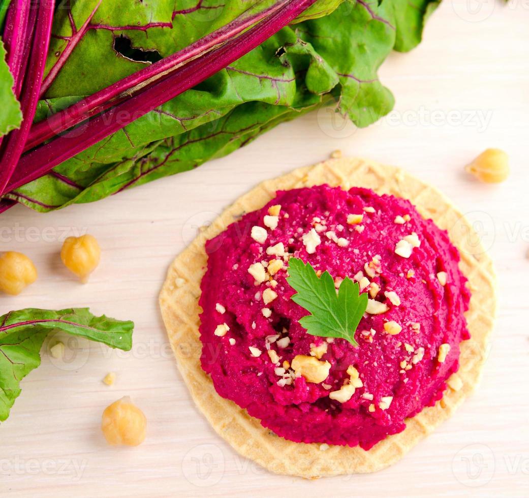 Beet hummus with peanuts and parsley on thin wafers photo