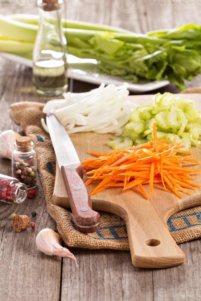 Sliced carrot, onion and celery on a chopping block photo
