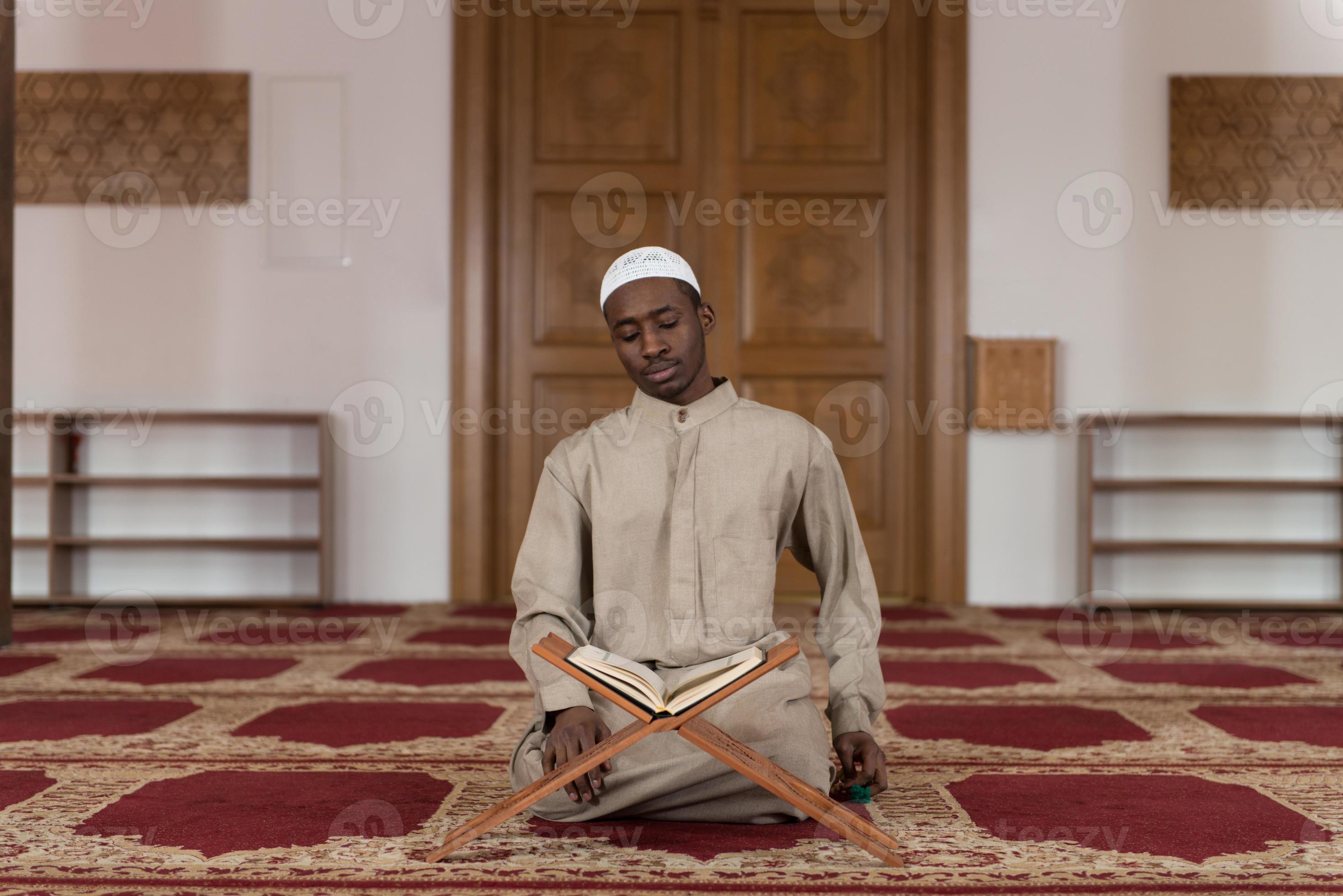 hombre musulmán en dishdasha está leyendo el Corán foto