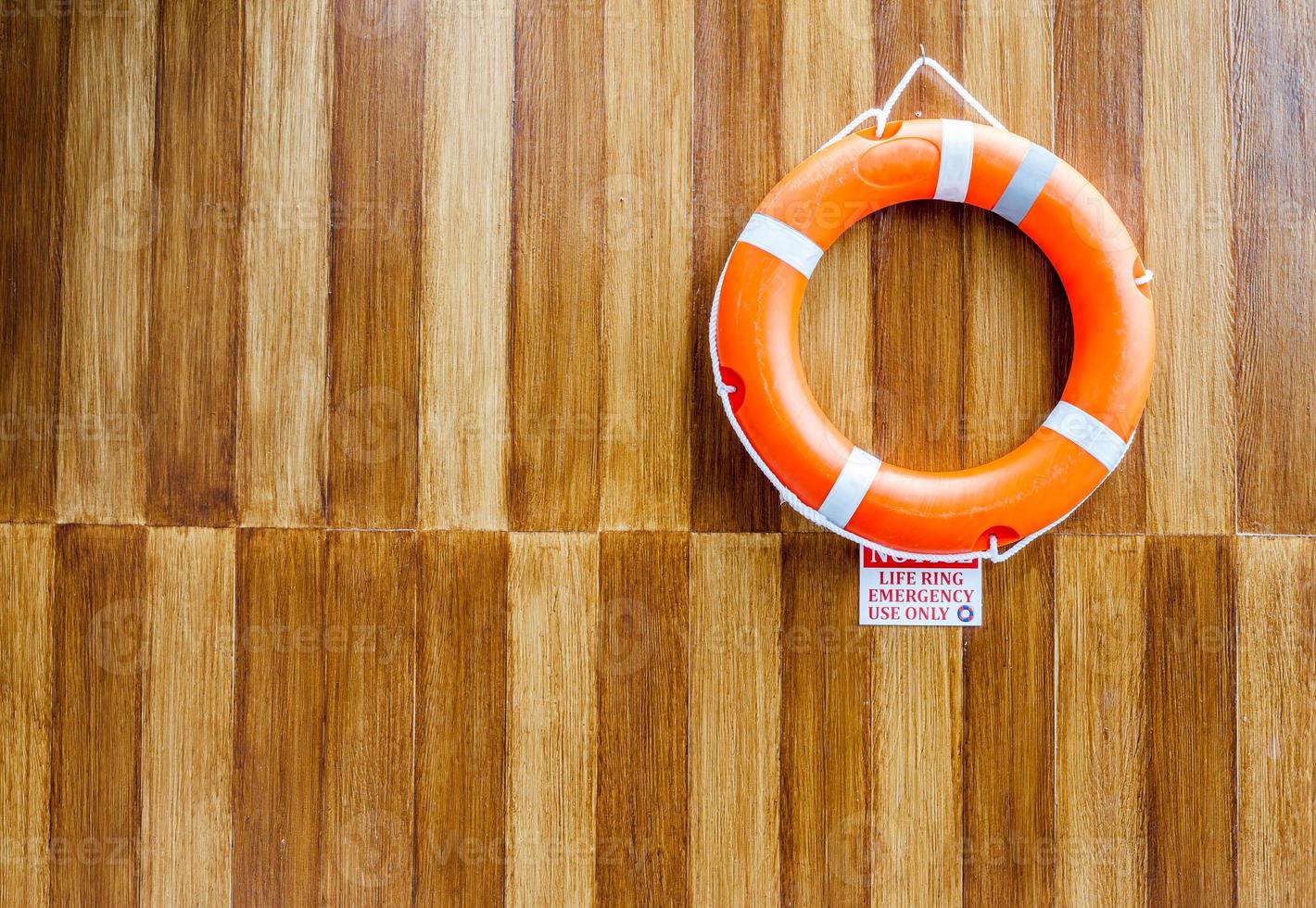 The orange life buoy on wood wall background photo