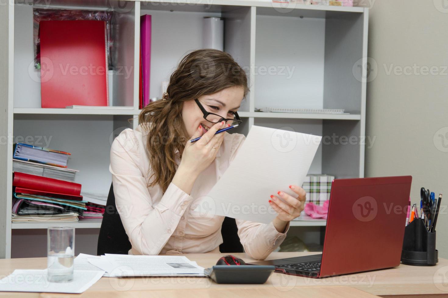 Girl laughs while reading a document in the workplace photo