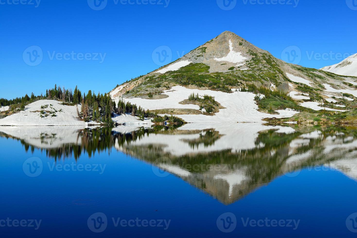 Cordillera nevada y lago alpino con reflejo foto