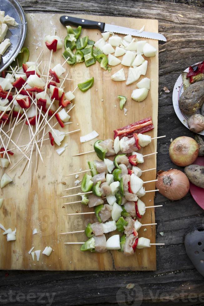 Preparatives for vegetable brochettes camping over a wooden table. photo
