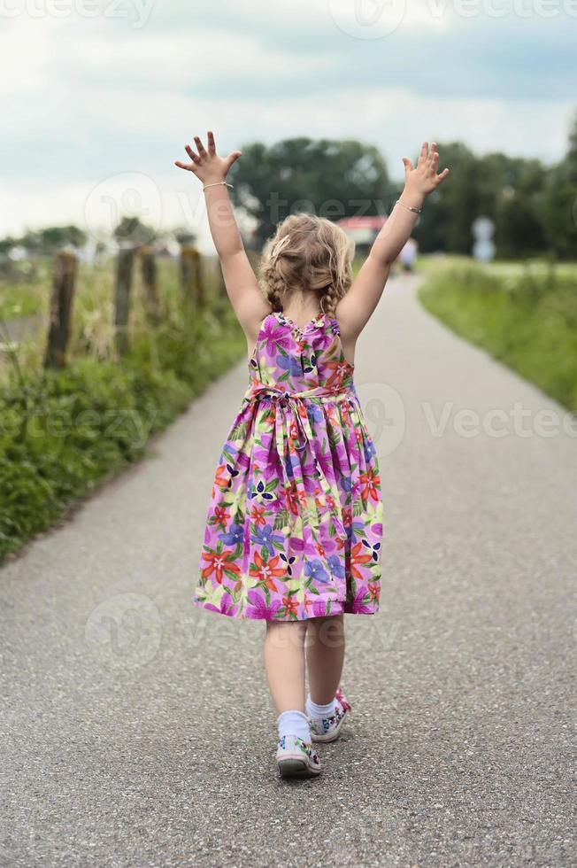 Niño caminando con sus manos en el aire foto