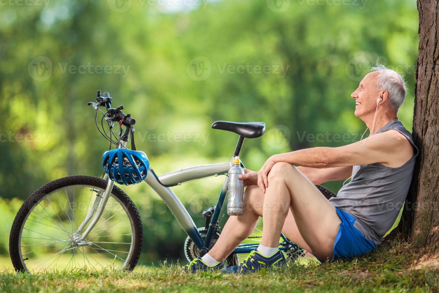 Senior cyclist sitting by a tree in a park photo