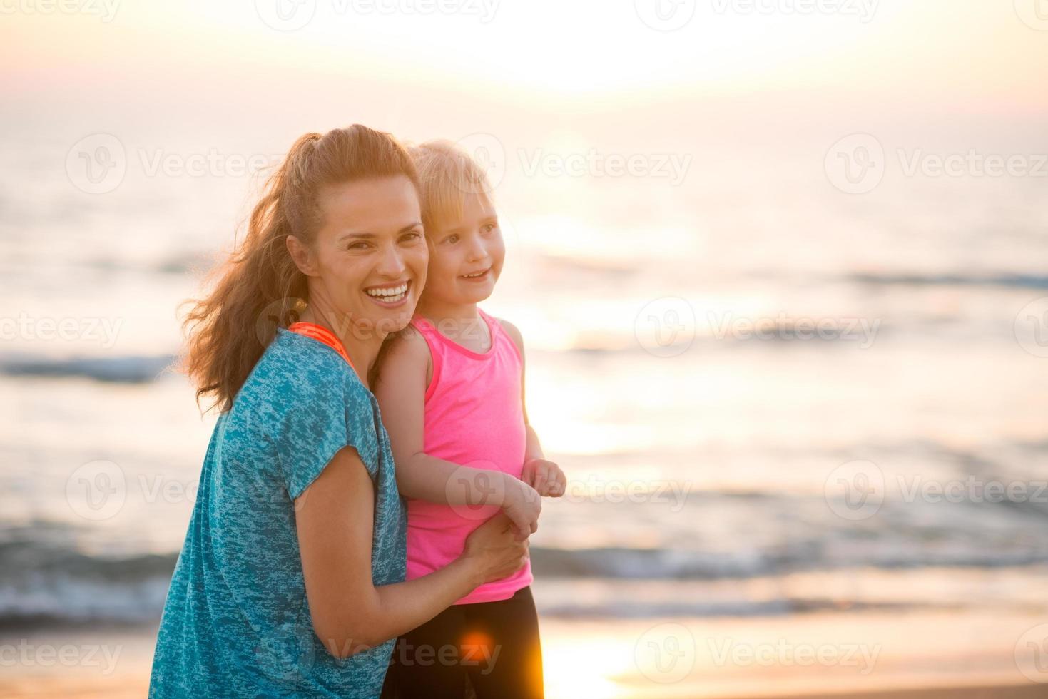 Retrato de feliz madre e hija en la playa al atardecer foto