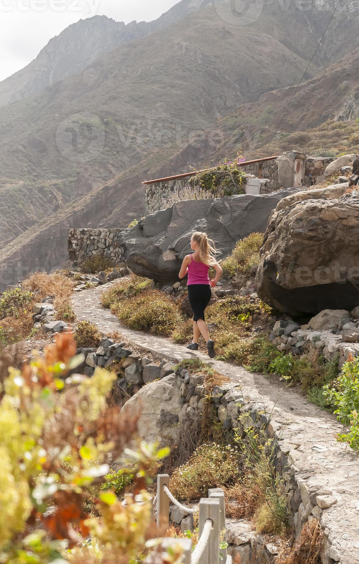 aptitud. mujer joven corriendo en una carretera de montaña foto