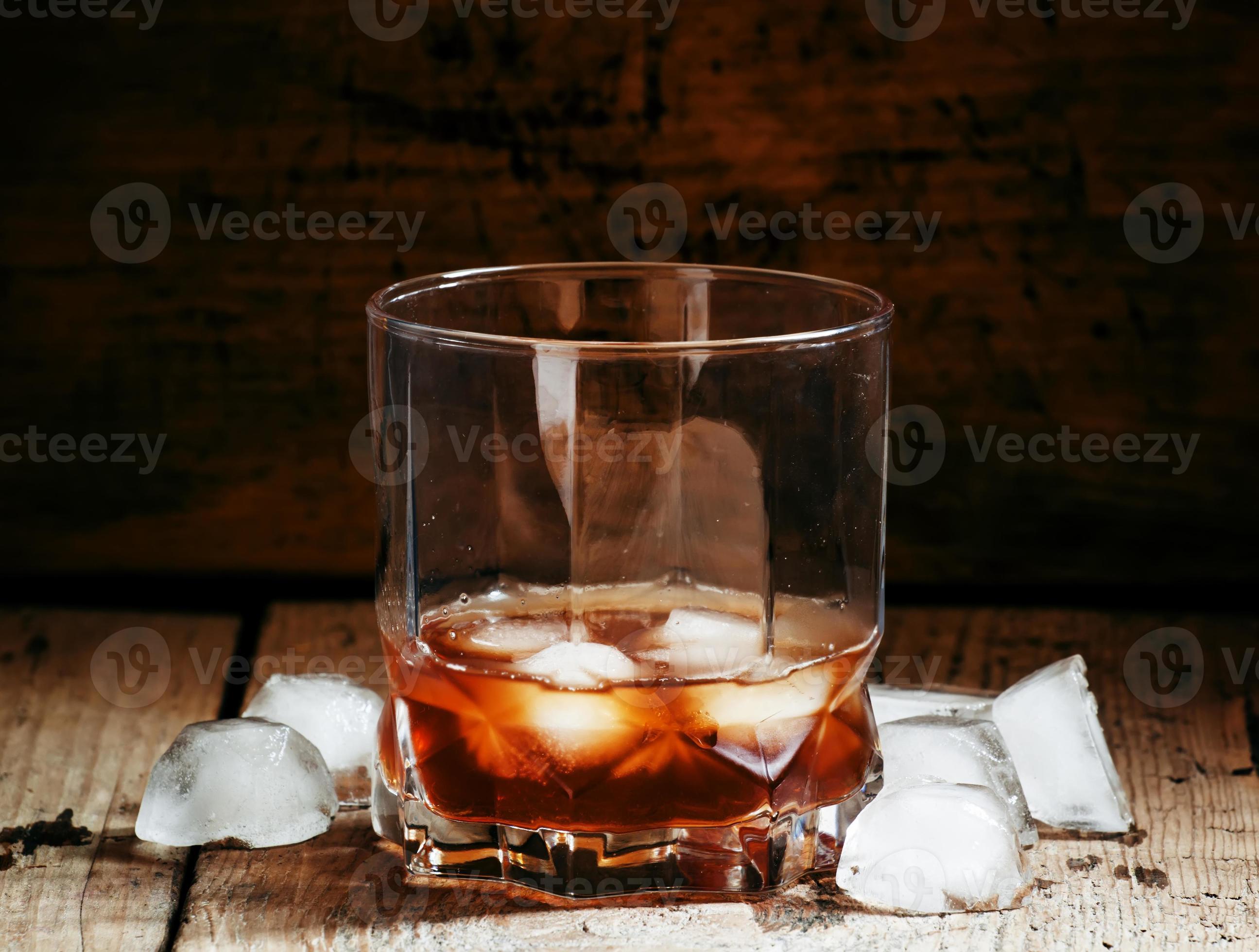 Cold whiskey with ice in a dark cellar photo