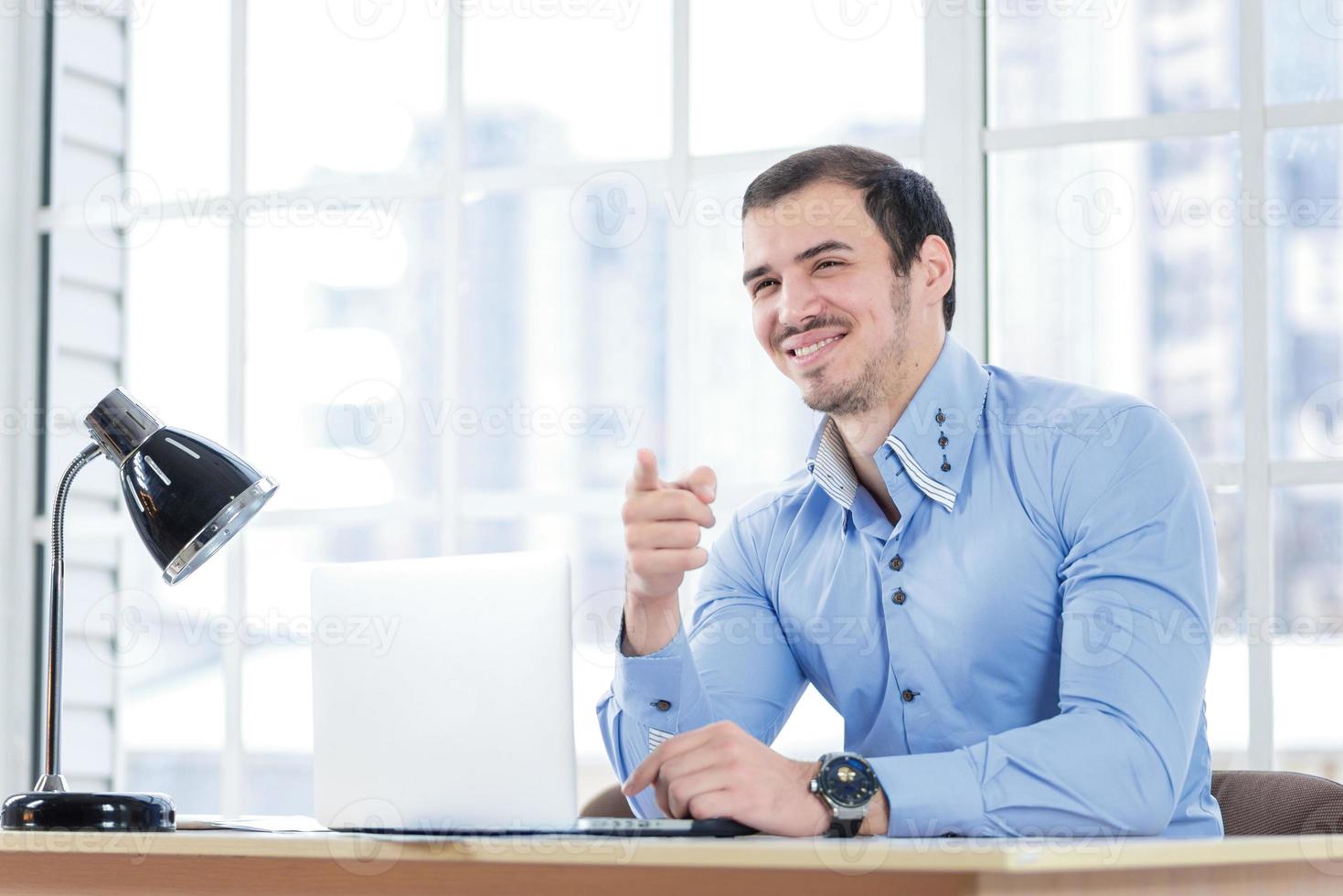 You're right. Smiling businessman working at his laptop and poin photo