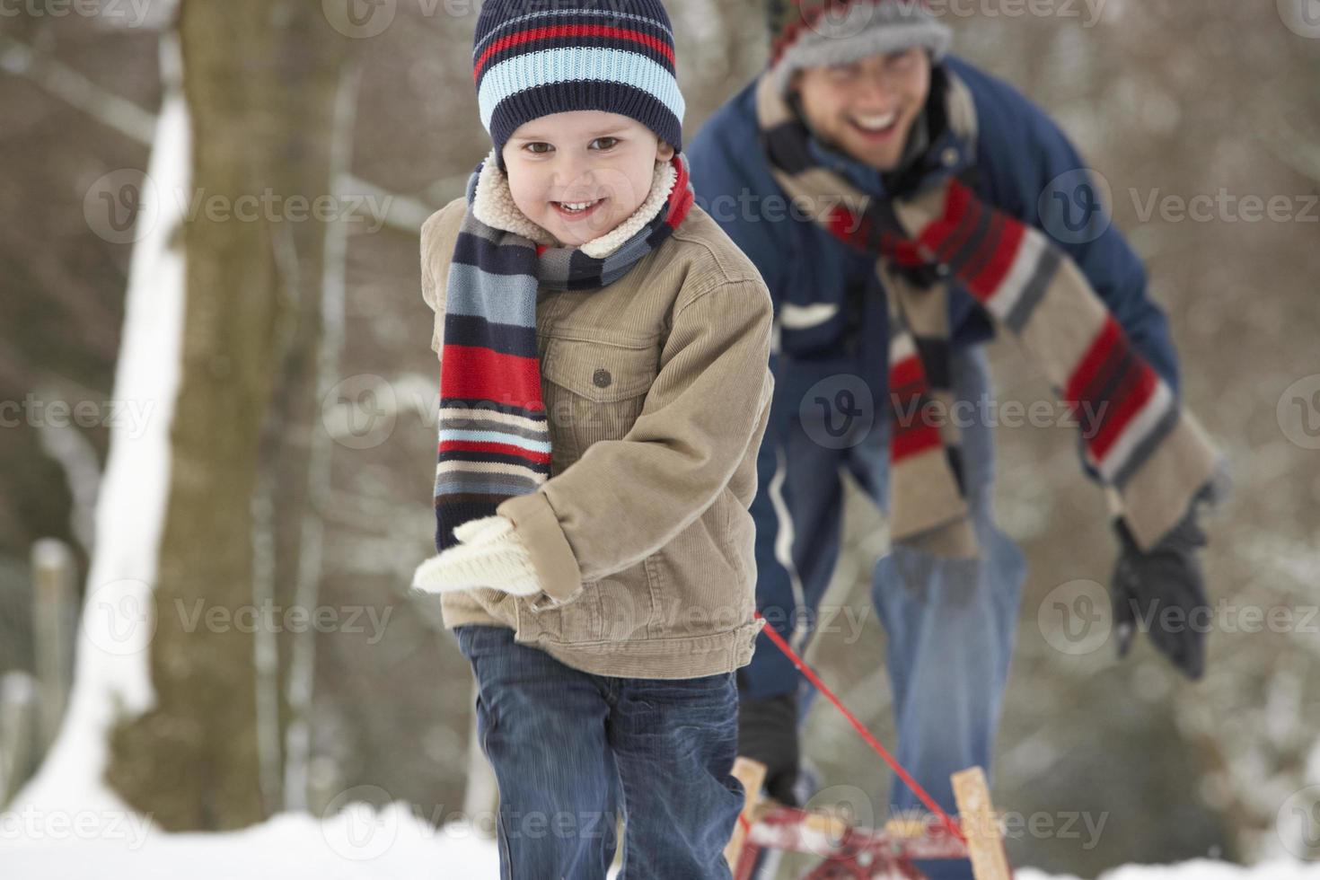 Niños tirando trineo a través del paisaje invernal foto