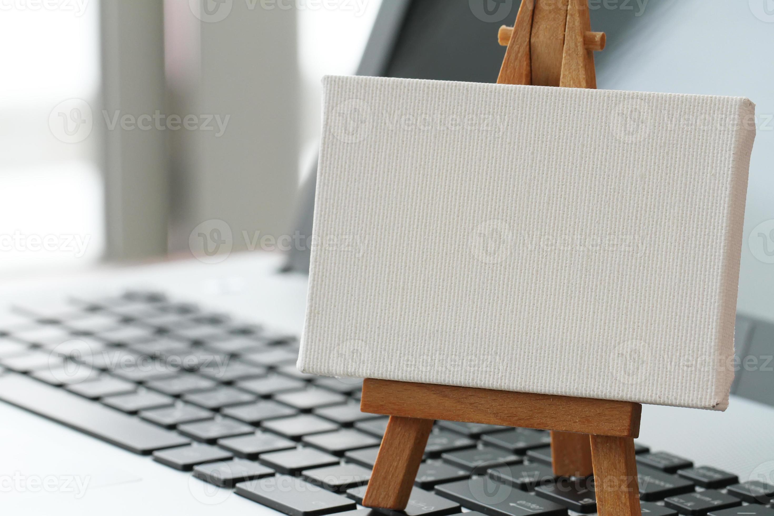 blank canvas and wooden easel on laptop computer as concept 861108